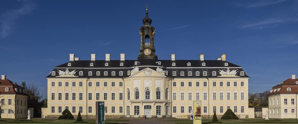 A large stately building with a prominent clock tower, symmetrical windows, and statues on the facade.