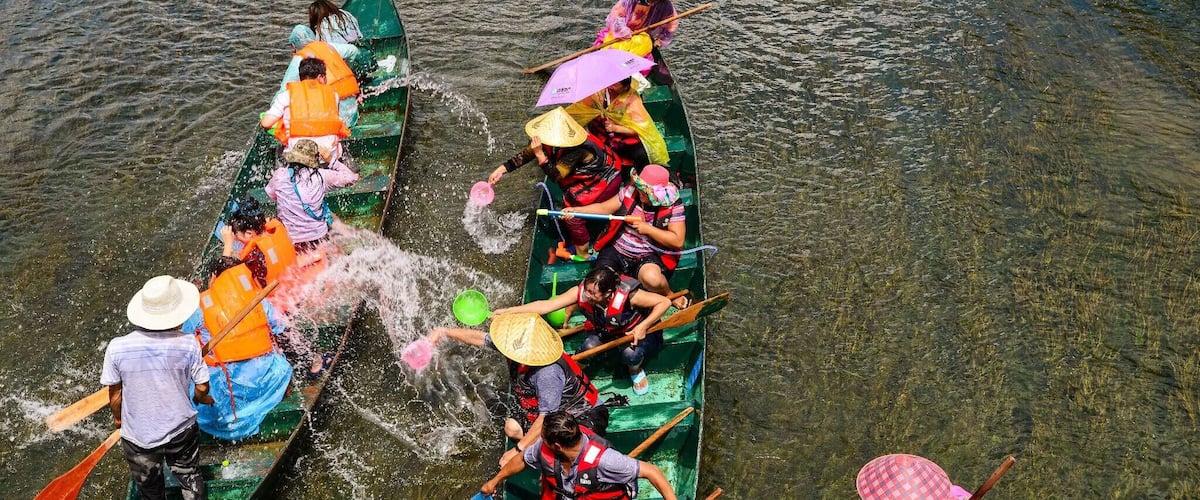 A group of people in traditional boats on a river.