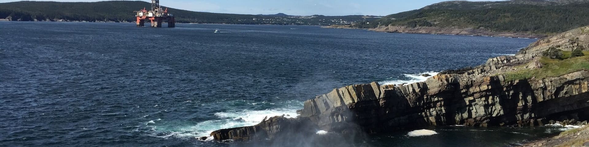 Hiking on the East Coast Trail. Sea spray on the rocks with an Oil Rig in the distance #ECT