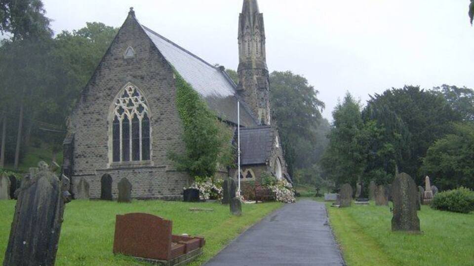 Una iglesia con un campanario alto y un cementerio con lápidas.