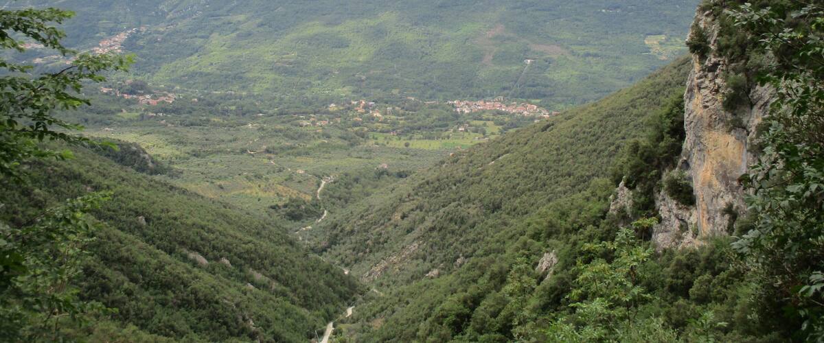 A mountainous landscape with a valley, a small town, and a cliff.