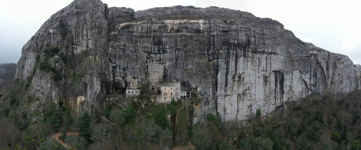 A large rock formation with a building nestled in its base.