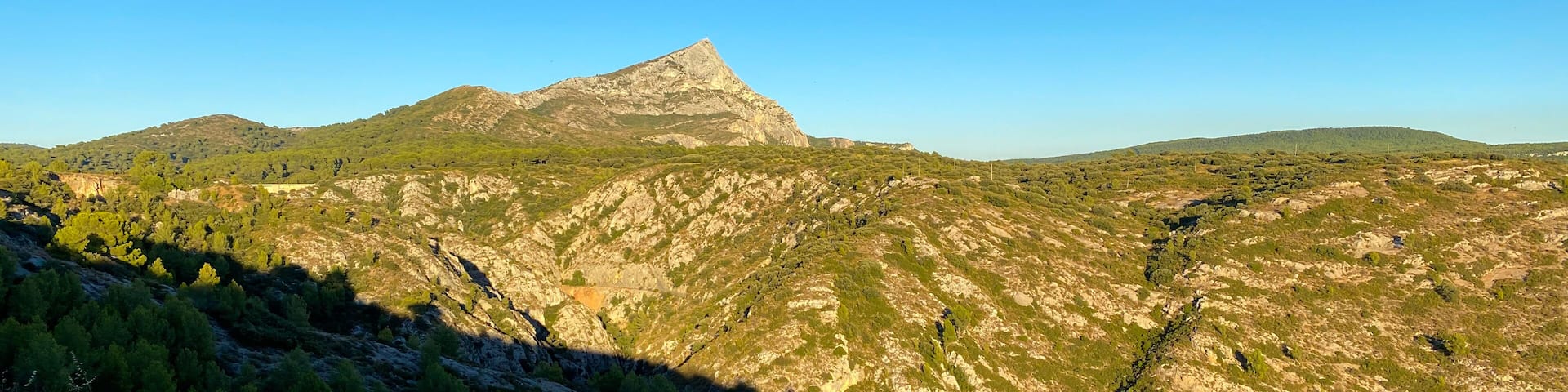 A mountainous landscape with a prominent peak and surrounding greenery.