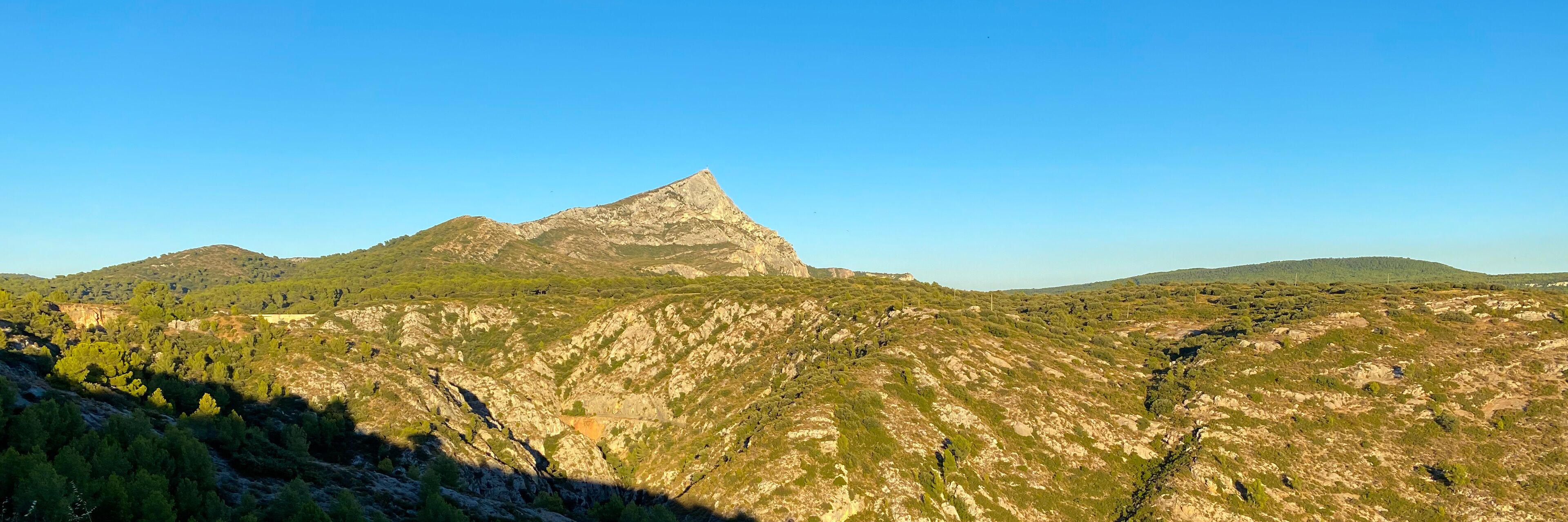 A mountainous landscape with a prominent peak and surrounding greenery.