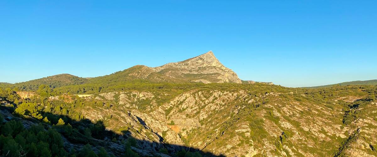 A mountainous landscape with a prominent peak and surrounding greenery.