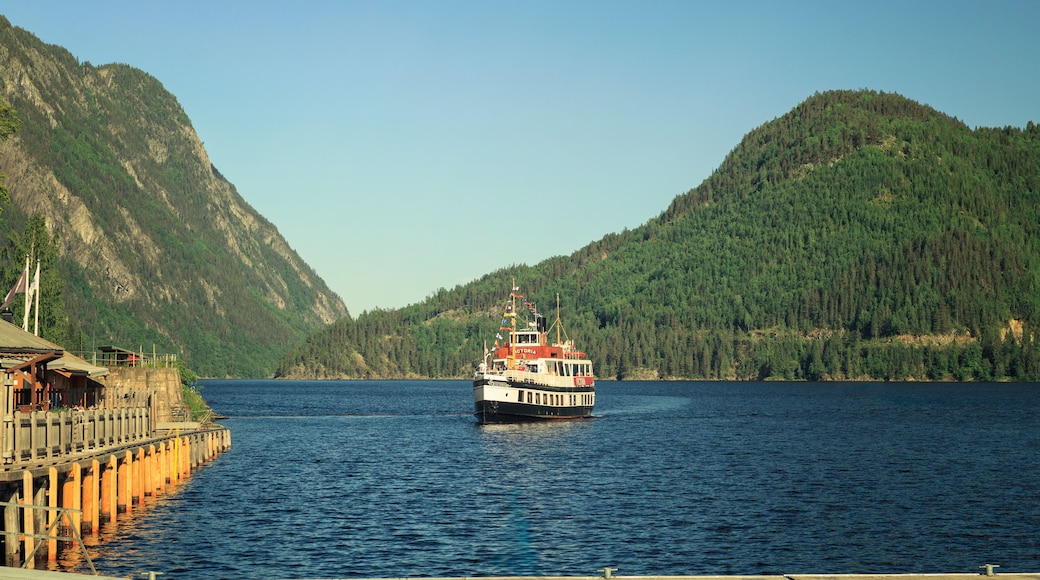 A boat named 'Victoria' on a calm lake surrounded by forested mountains.