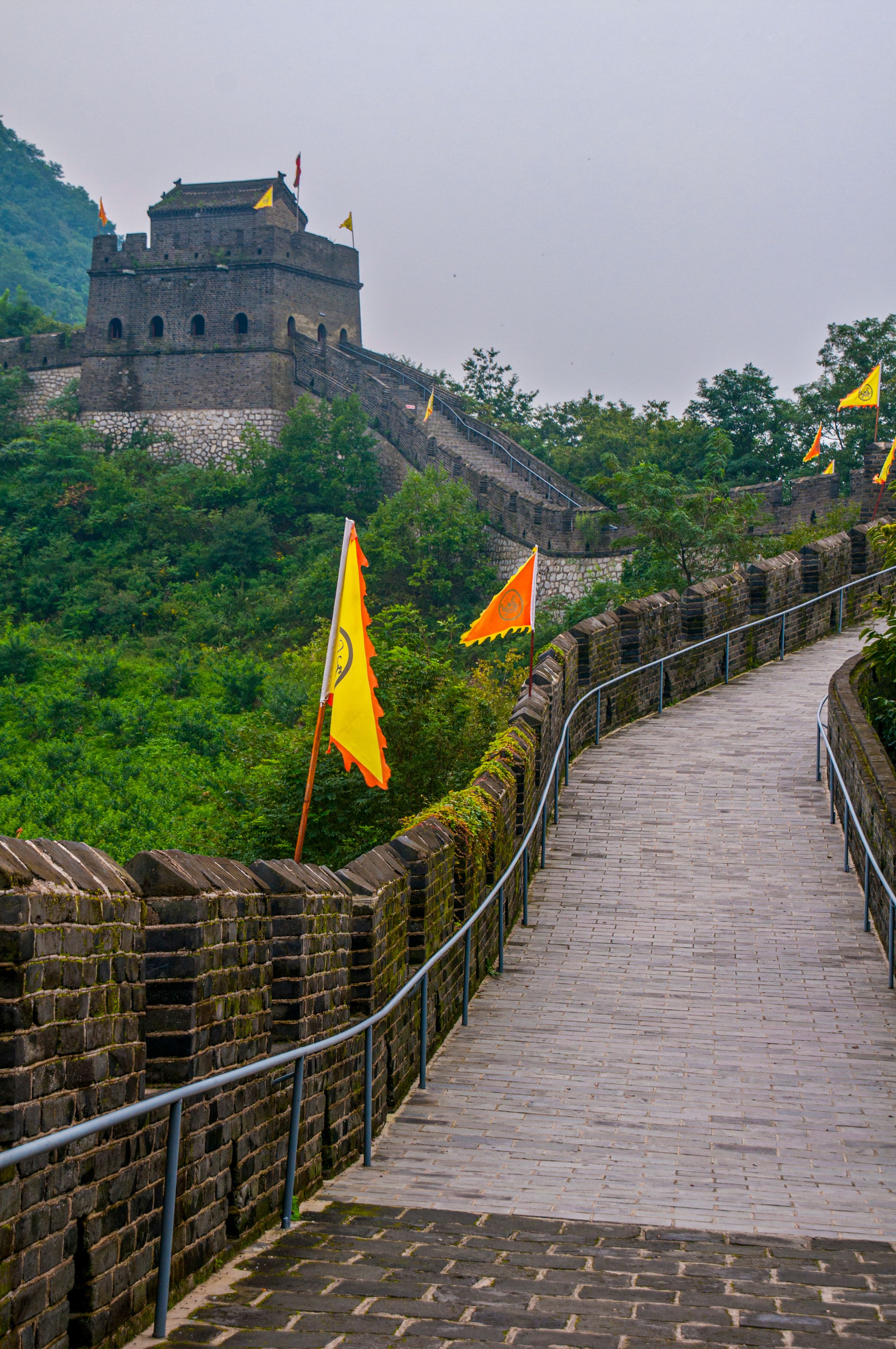 A stone pathway leading to a historic fortress with flags.