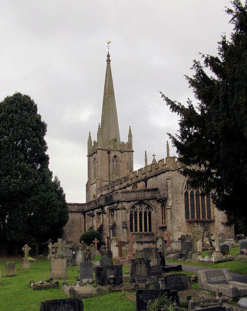 A historic church with a tall spire and surrounding graveyard.