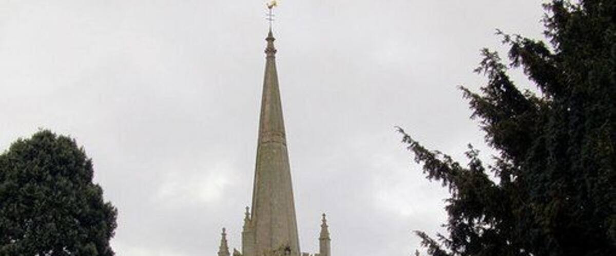 A historic church with a tall spire and surrounding graveyard.