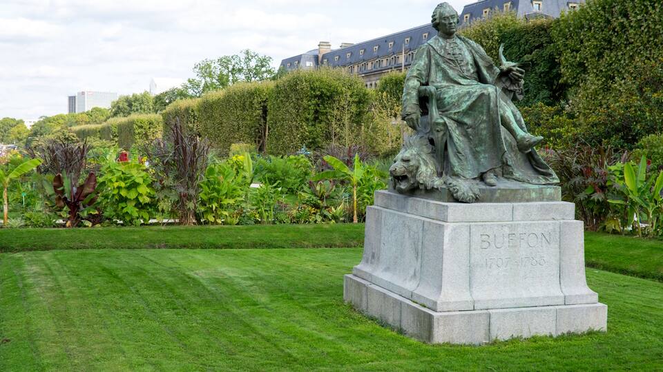 A statue of a man with a lion in a park with green grass and trees.