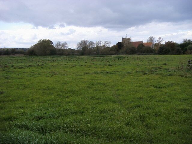 A green field with a church in the distance.