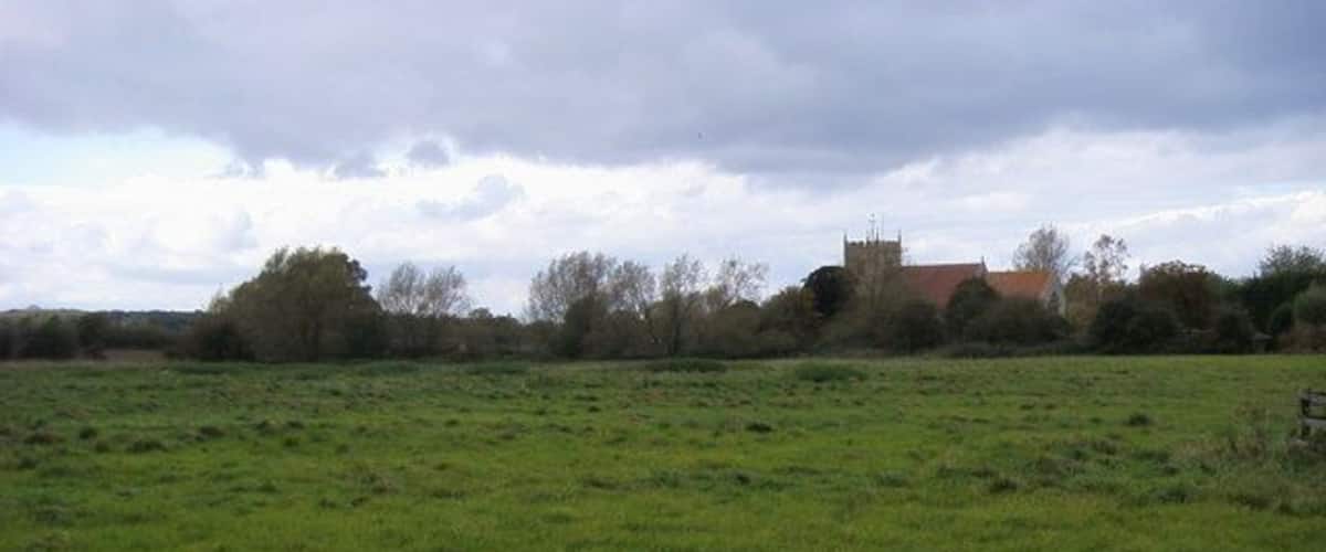 A green field with a church in the distance.
