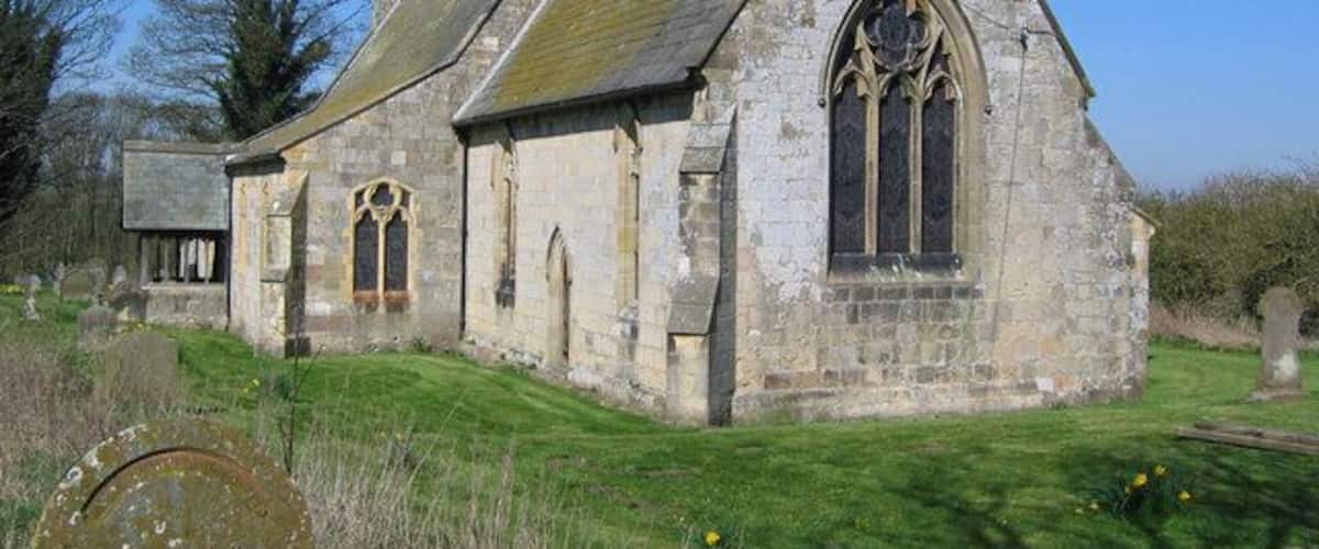 A stone church with a bell tower and a large arched window.
