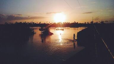 A sunset over a calm river with a bridge in the foreground.