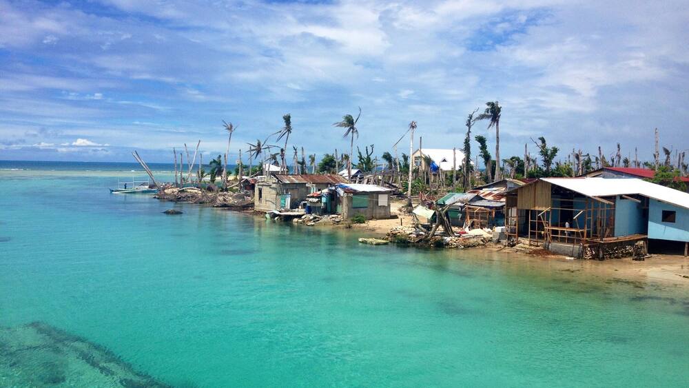 A coastal village with clear turquoise waters and palm trees.