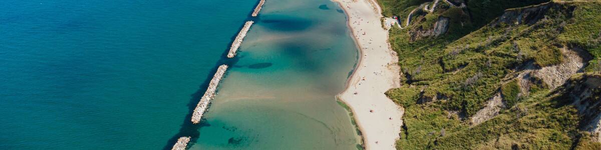 A coastal landscape with a beach, a pier, and a cliffside.