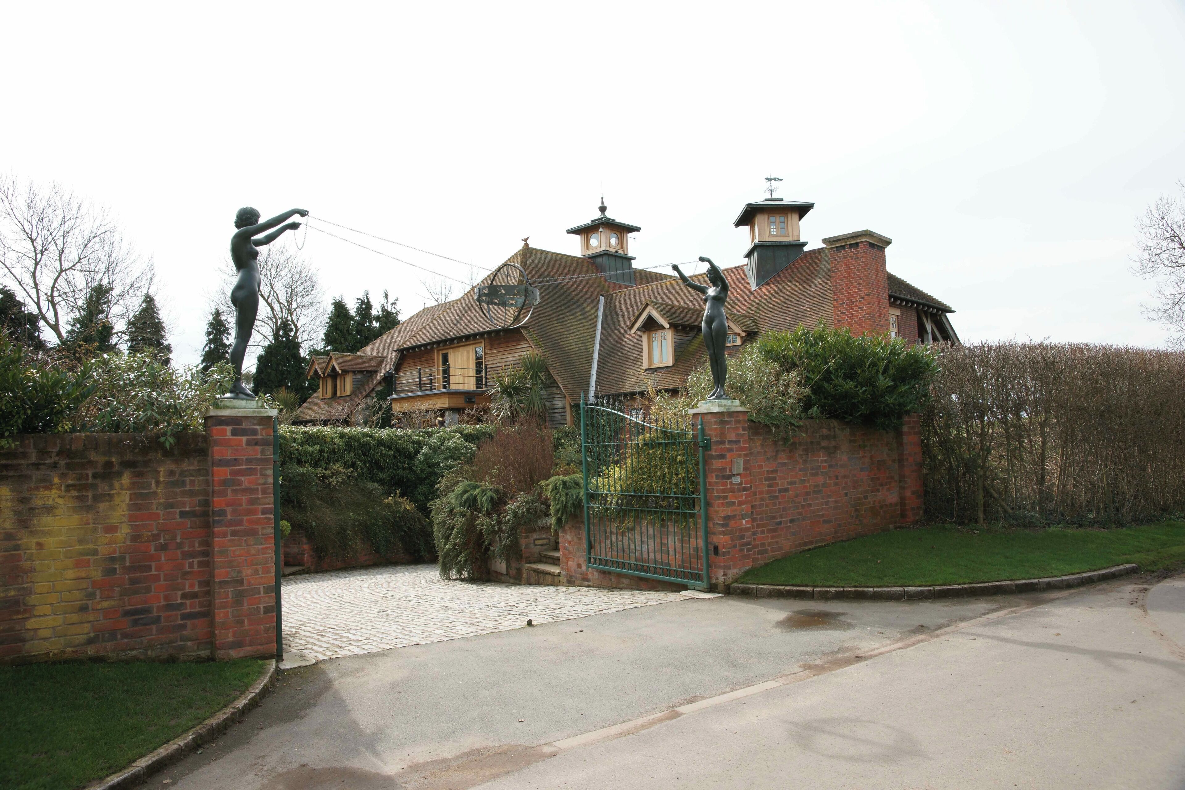 A large house with a brick wall and a green gate.