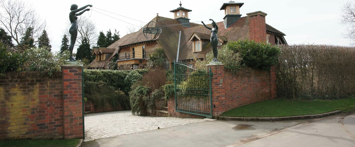 A large house with a brick wall and a green gate.