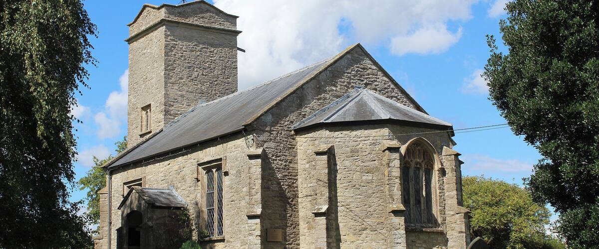 A stone church with a bell tower and a weather vane.