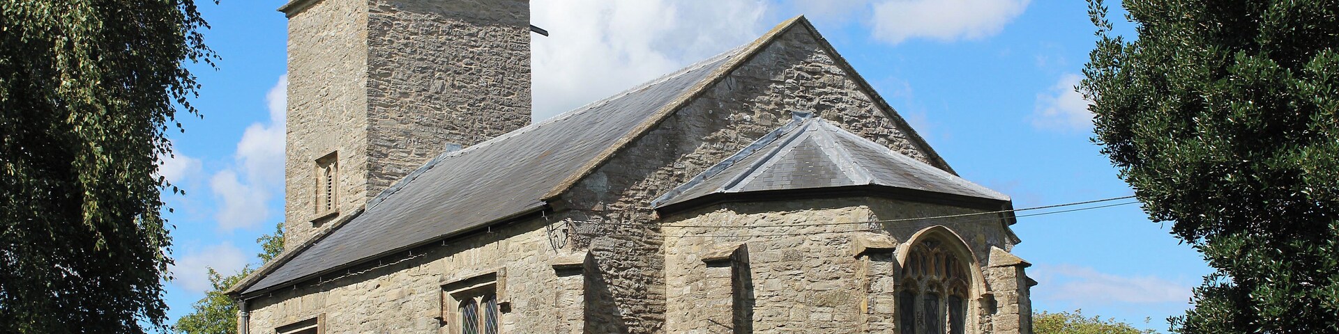 A stone church with a bell tower and a weather vane.