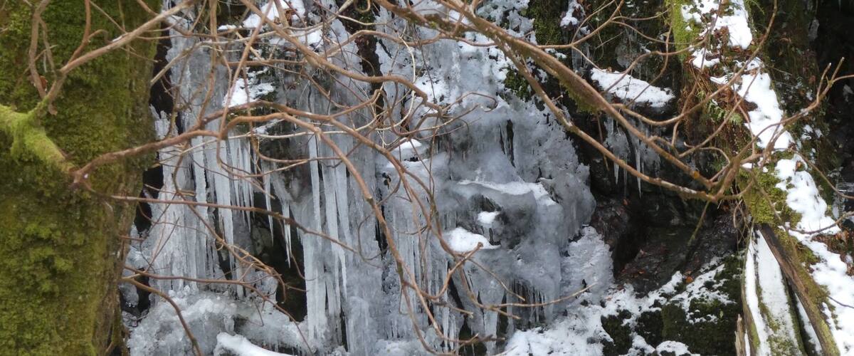 A frozen waterfall with icicles and snow-covered rocks.