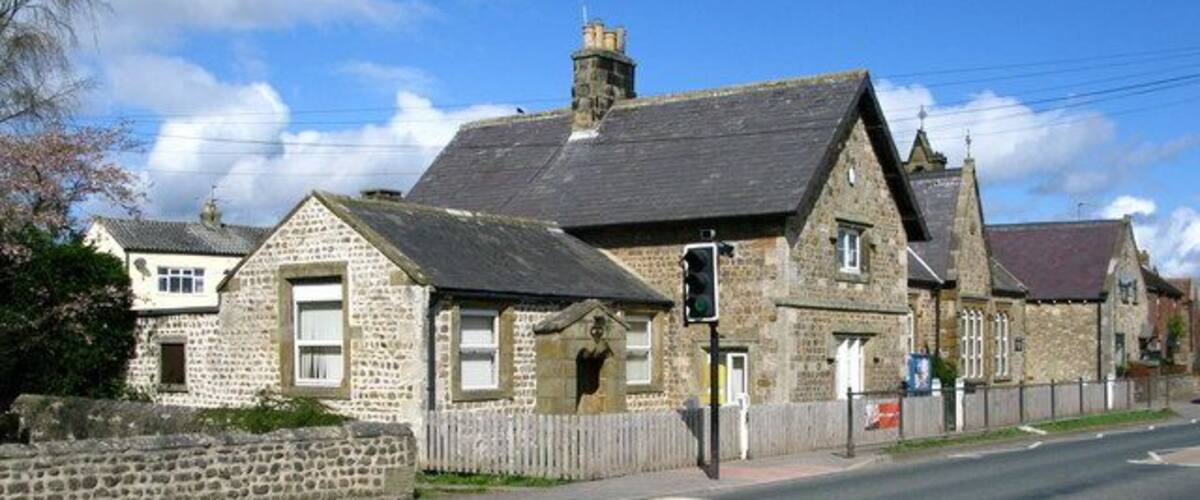 A stone building with a traditional design, a street, and a clear blue sky.