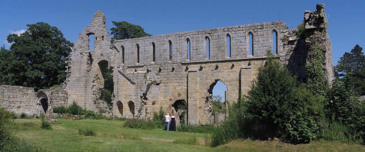 A historic stone building with arched windows and ruins.