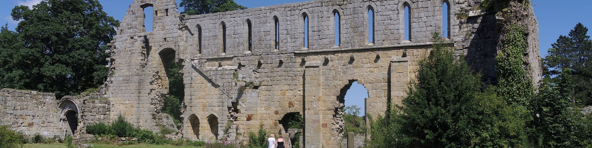 A historic stone building with arched windows and ruins.