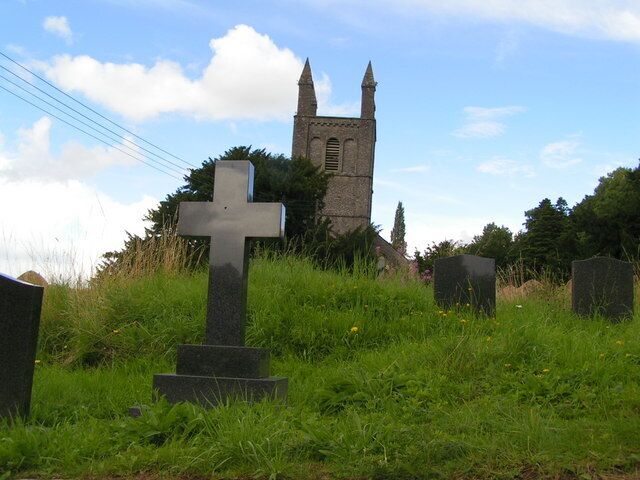 A cemetery with a prominent cross and a church tower in the background.