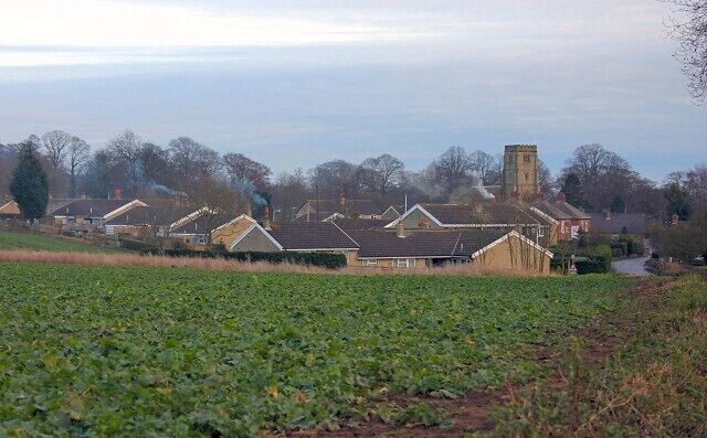 A rural landscape with houses, a church tower, and a field.