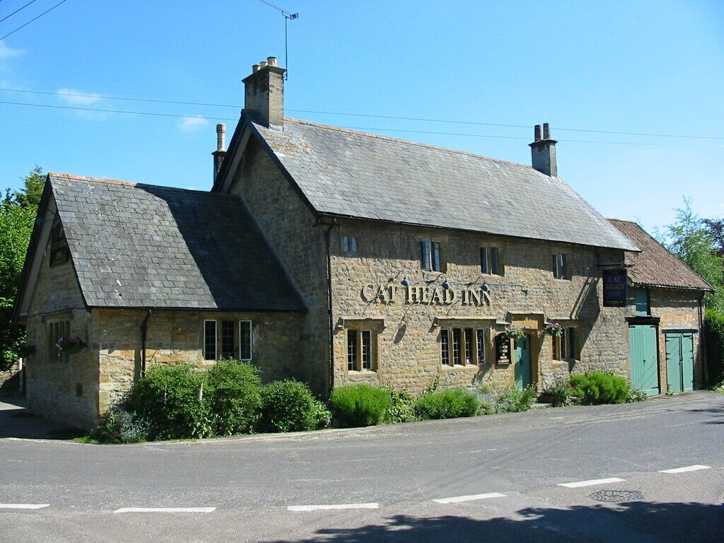 A stone building with a sign reading "Cat Head Inn" on a sunny day.