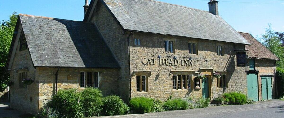 A stone building with a sign reading "Cat Head Inn" on a sunny day.