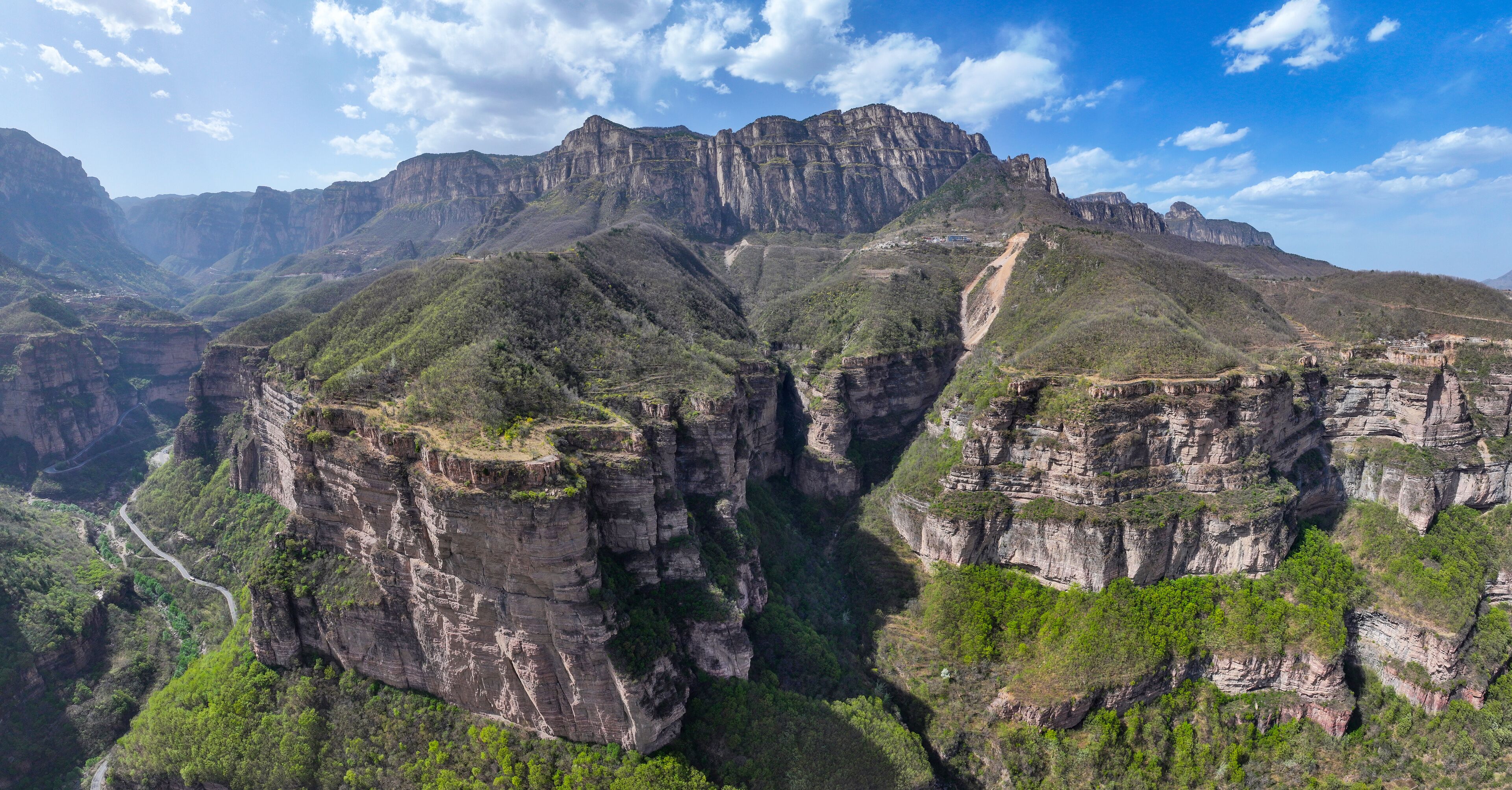 A canyon with steep cliffs and a winding road.