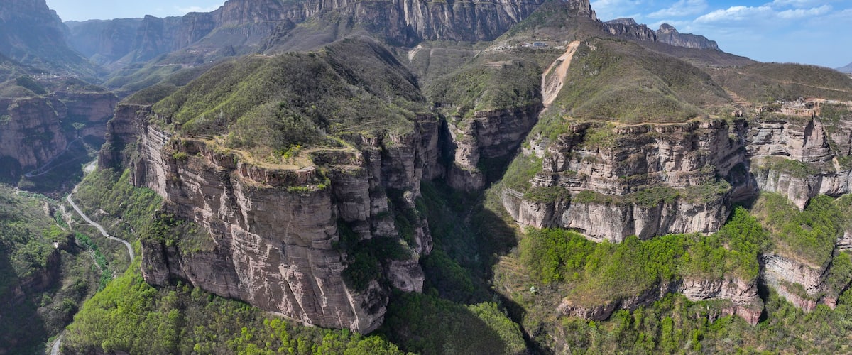 A canyon with steep cliffs and a winding road.