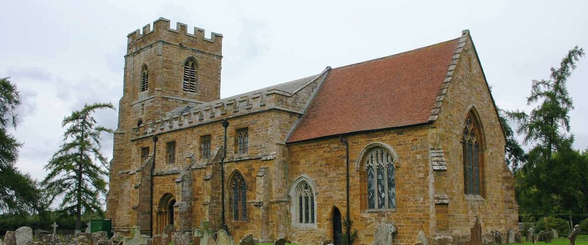 An old stone church with a bell tower and a red-tiled roof.