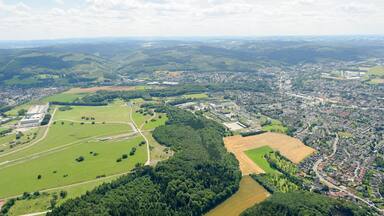Luftaufnahme: Links Deilinghofen, westlicher Bereich des Naturerlebnisgebiet Hemer-Apricke der NRW-Stiftung mit ehemaligen Panzerstraßen des Standorttruppenübungsplatzes, dahinter Hemer mit Sauerlandpark und ehemasliger Blücher Kaserne in der Bildmitte