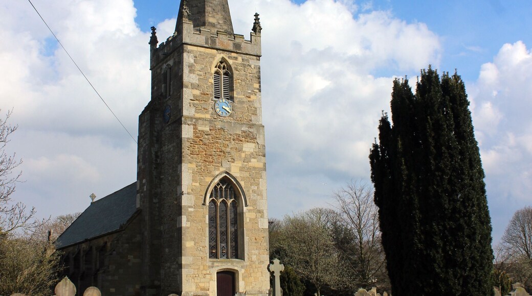 Una iglesia con un campanario alto y un reloj, rodeada por un cementerio con lápidas.