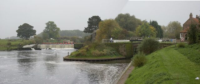 A river with a lock, a bridge, and a house on a grassy bank.