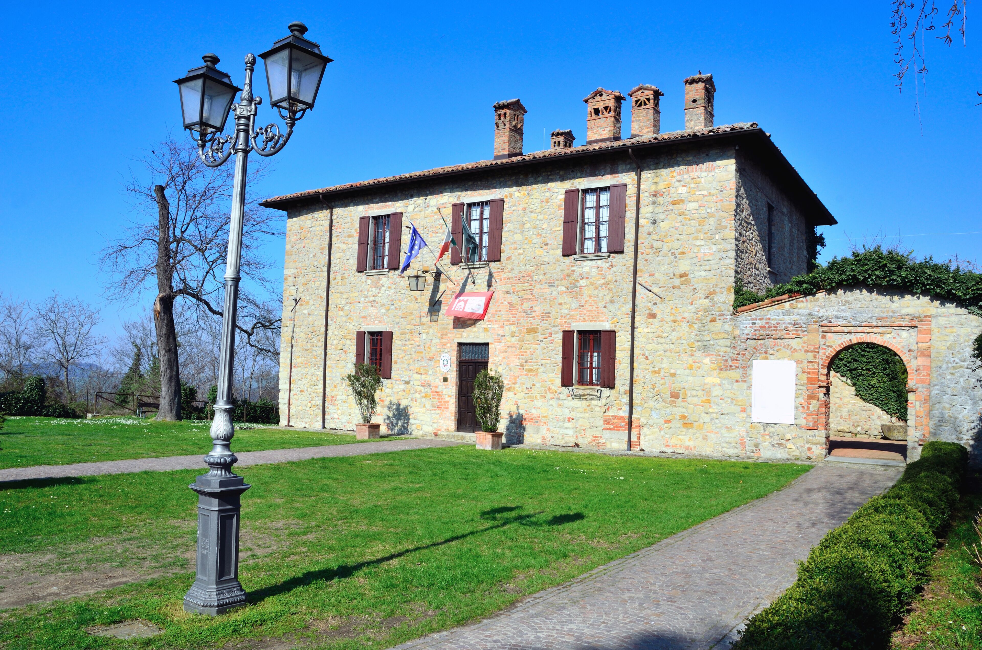 A stone building with a paved pathway, a lamp post, and a small archway.