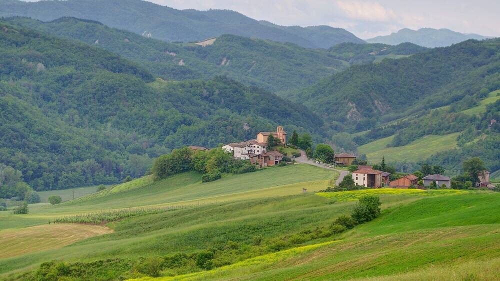 A rural landscape with rolling hills, a small village with traditional buildings, and a prominent church tower.