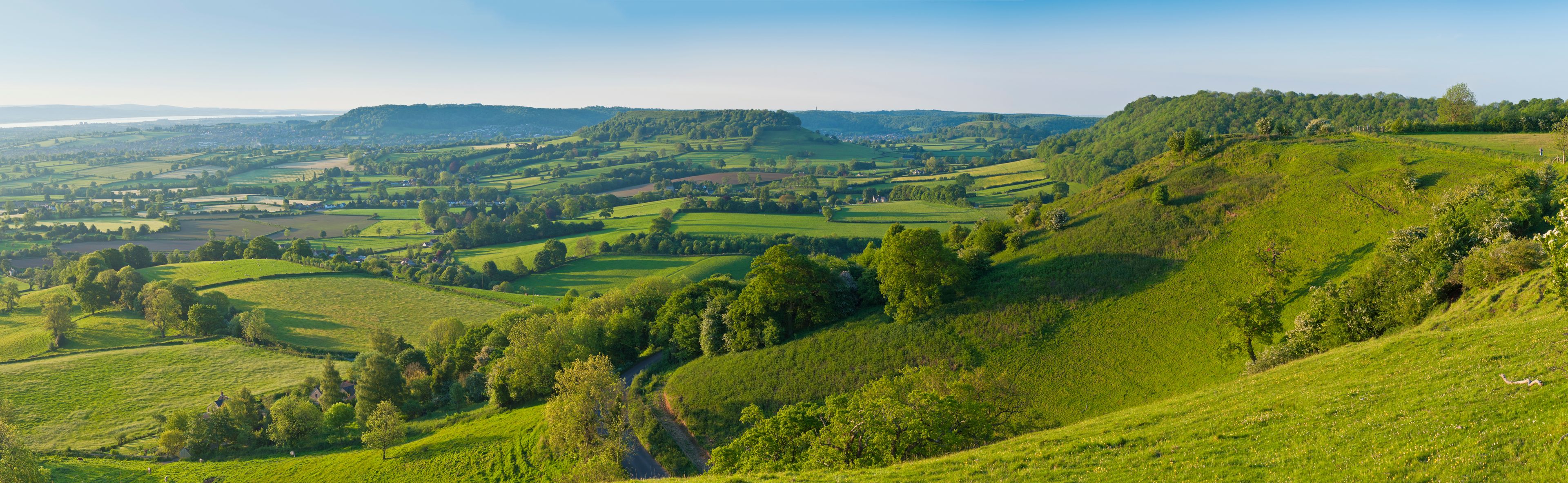 Rolling green hills, a winding road, and a distant village.