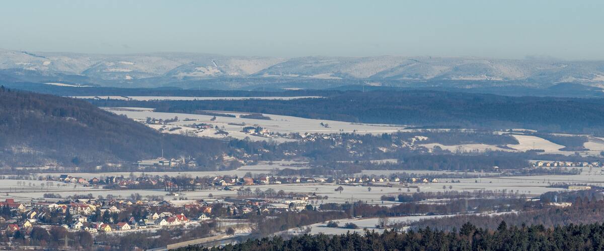 A snow-covered landscape with a town nestled in the valley, surrounded by mountains.