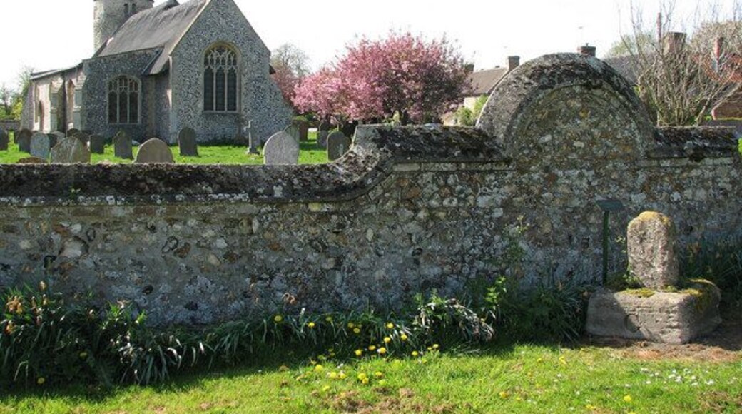 St Mary's church The remains of a medieval stone cross can be seen in foreground (right). Many prehistoric tools, Saxon jewellery and Roman coins have been unearthed in the area and there are also the remains of two medieval crosses bearing witness to regular markets having taken place on the village green and at the crossroads. St Mary's church > https://www.geograph.org.uk/photo/1269098 - https://www.geograph.org.uk/photo/1269159 - https://www.geograph.org.uk/photo/1269163 is located at the end of the large village green. It has a thatched roof and its round tower > https://www.geograph.org.uk/photo/1269095 dates from the early 11the century and is believed to be one of the earliest in Norfolk which is topped by an early 15th century octagonal bell stage. Inside, the bell window is off-centre. The interior was restored during Victorian times but two old brasses have survived. The pulpit > https://www.geograph.org.uk/photo/1269184 is Jacobean. There is also an interesting altar chest > https://www.geograph.org.uk/photo/1269173 in the south aisle which was made by J. Bramah & Son, London, and is dated to 1835. The perhaps most interesting feature contained in this church are two pieces of graffiti (protected behind perspex) believed to have been made by a mason on blocks of stone which around 1340 were built into the south wall so that the south aisle > https://www.geograph.org.uk/photo/1269165 could be added. The depiction of a devil > https://www.geograph.org.uk/photo/1269196 is described by archaeologists as among the best in the country. For more information see http://www.norfolkchurches.co.uk/beachamwellmary/beachamwellmary.htm