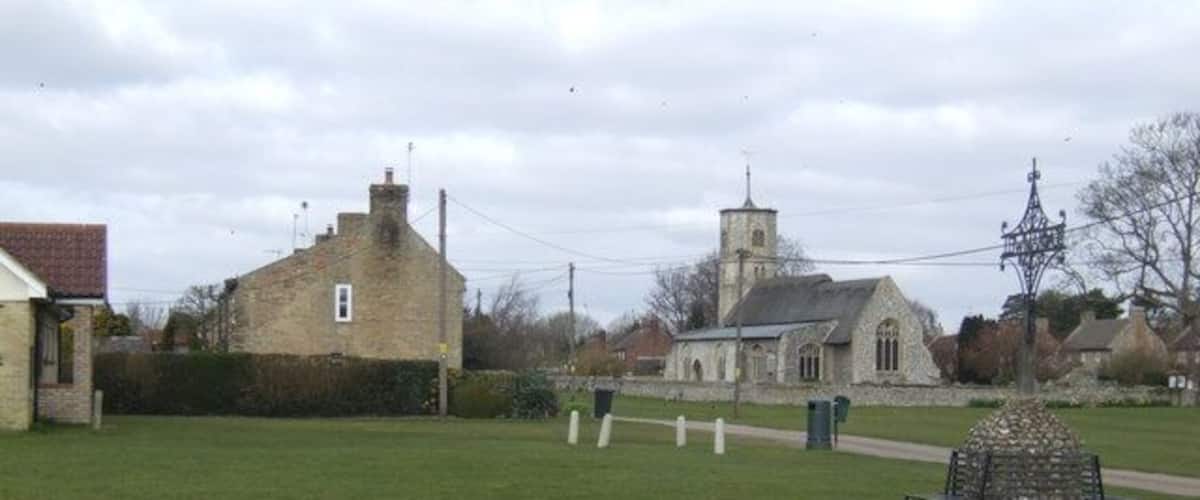 A grassy field with a stone church and a stone building in the background.