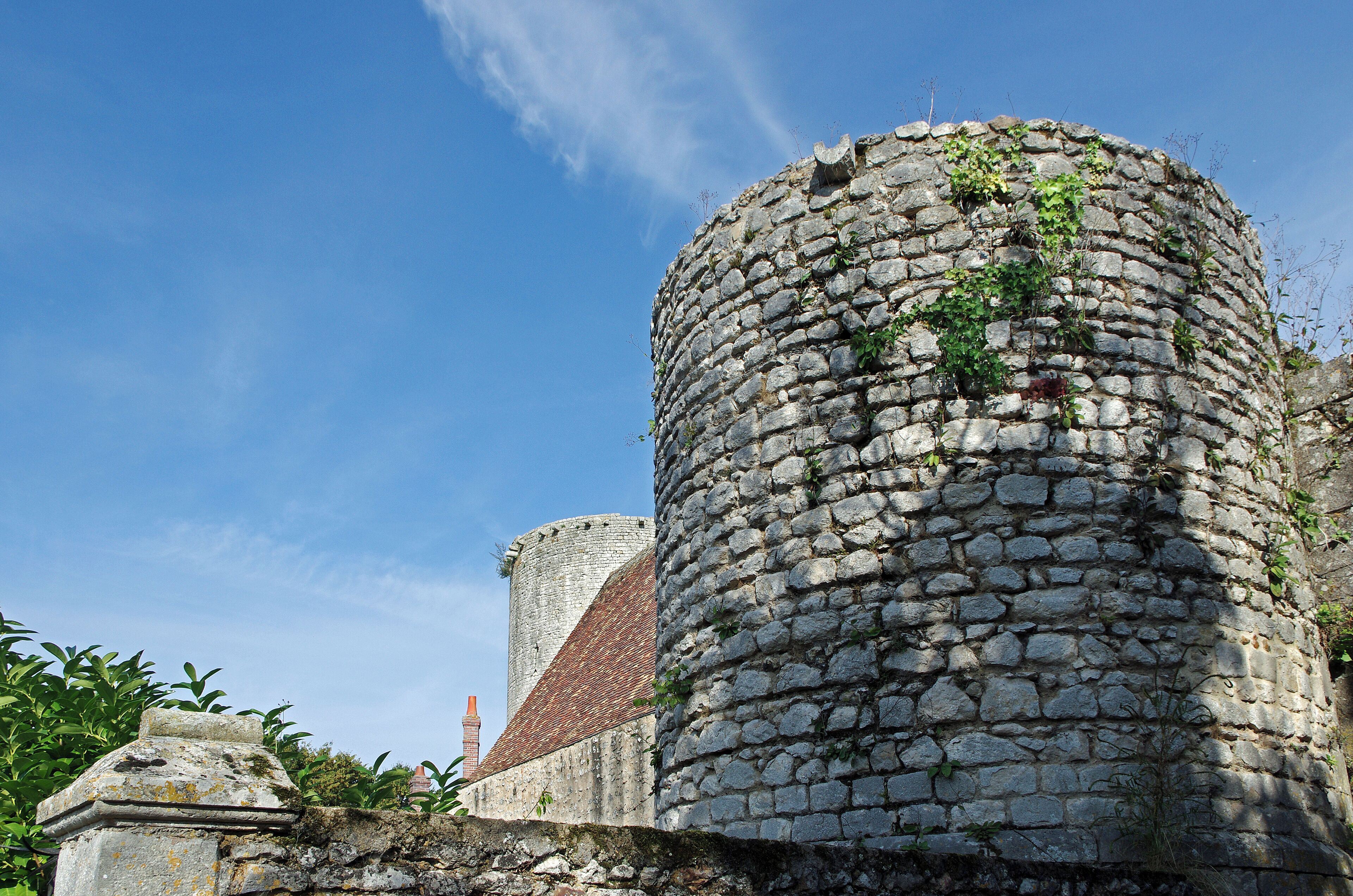A stone tower with a brick roof, surrounded by greenery.