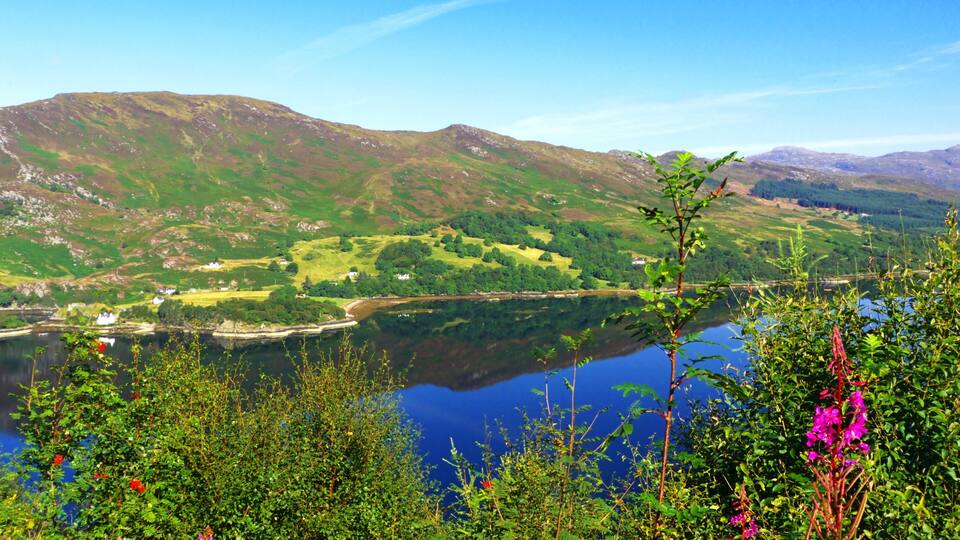 A lake surrounded by green hills and mountains.