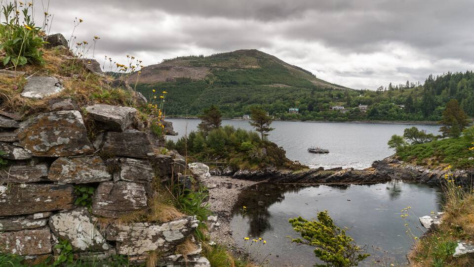 A stone wall, a lake, and a forested hill.