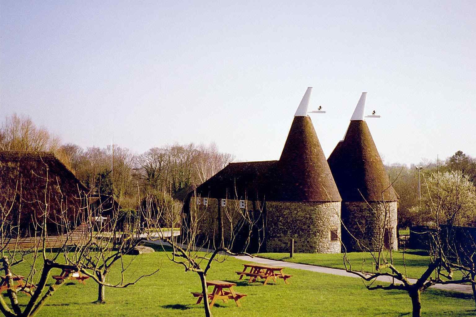 A building with two conical towers and a picnic table in a grassy area.