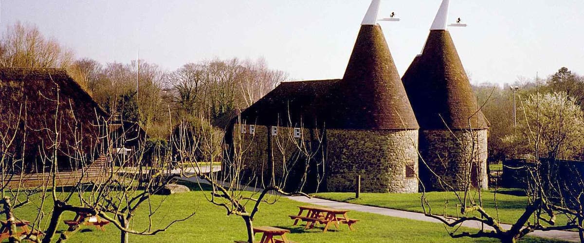 A building with two conical towers and a picnic table in a grassy area.