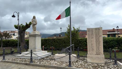 War Memorial in Accettura, Italy with Statue, Cannon and Italian Flag on a Cloudy Day. Matera, Basilicata, Lucania, Italy